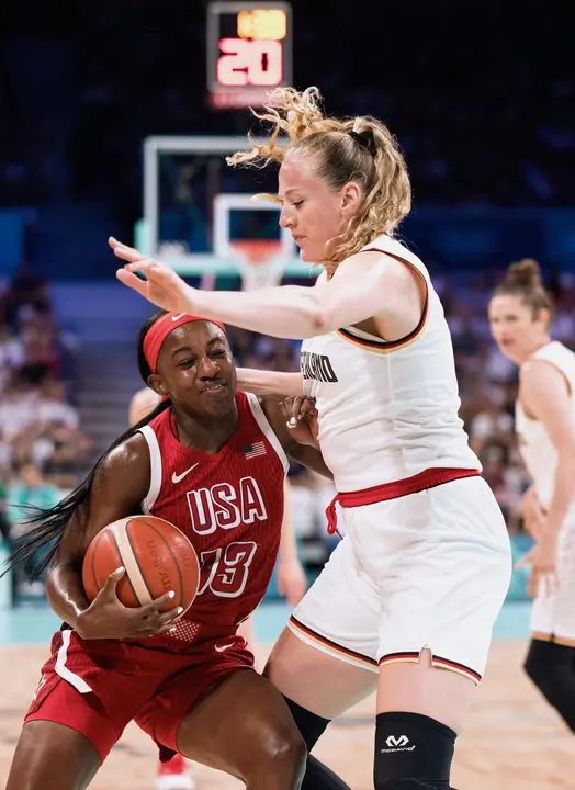 Villeneuve D'asq (France), 04/08/2024.- La estadounidense Jackie Young (i), m&aacute;xima anotadora del partido del torneo ol&iacute;mpico de baloncesto que las grandes favoritas ganaron a Alemania, defendida por Marie Guelich (d) en el estadio Pierre Mauroy de Villeneuve-d'Ascq. EFE/EPA/ALEX PLAVEVSKI