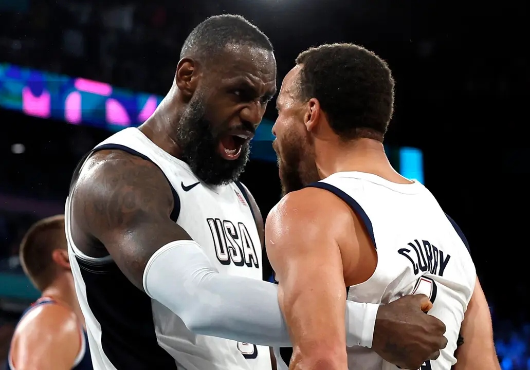 Los estadounidenses Lebron James (izq.) y Stephen Curry celebran la victoria en el partido de semifinales ante Serbia, del torneo de baloncesto de Par&iacute;s 2024. EFE/EPA/YOAN VALAT