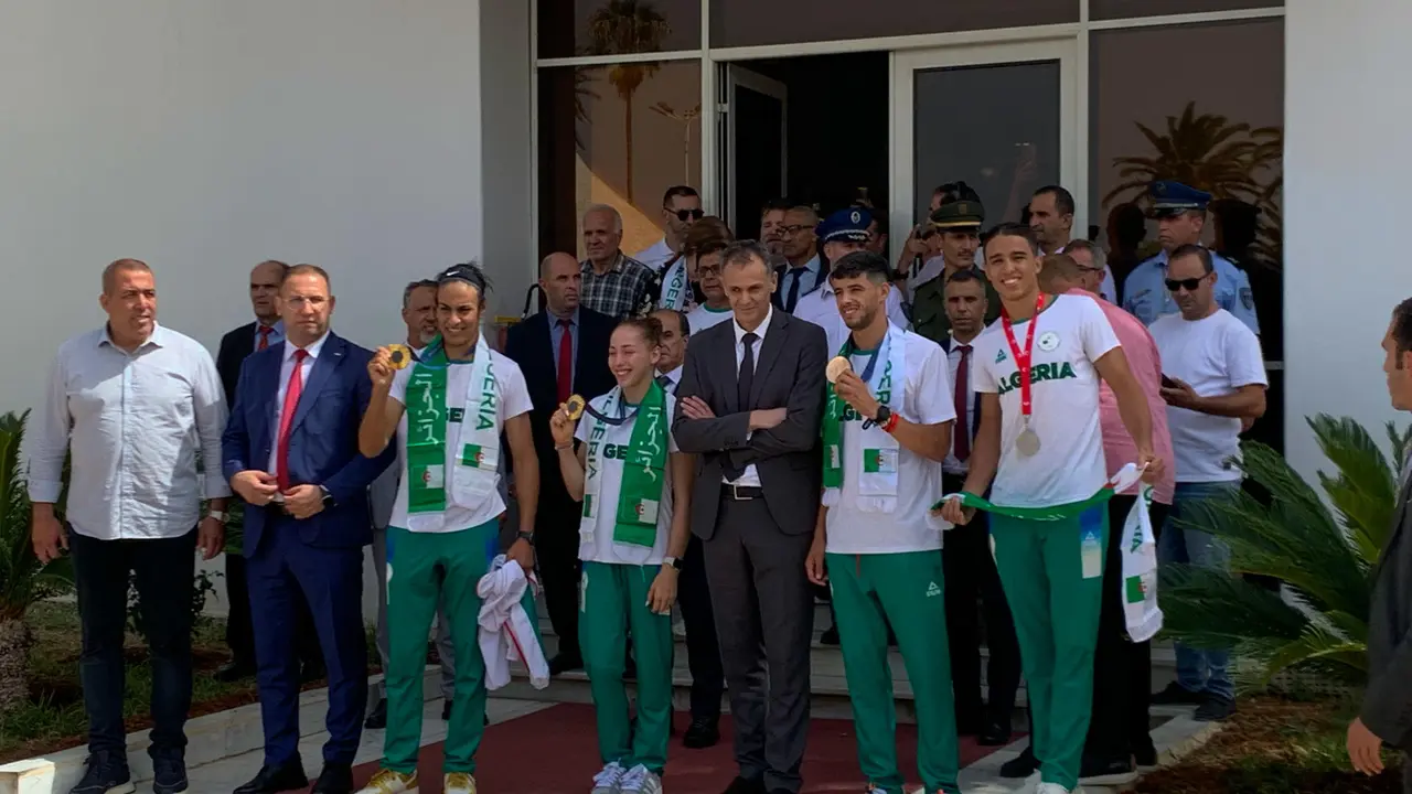 (izda a dcha) Imane Khelif, medalla de oro en boxeo femenino -66 kilogramos; Kaylia Nemour, oro en barras asim&eacute;tricas y Djamel Sjati, medallista de bronce ol&iacute;mpico en los 800 metros posan durante una recepci&oacute;n con el ministro argelino de Deportes, Abderrahmane Hammad, durante una  recepci&oacute;n en el aeropuerto de Argel de los medallistas ol&iacute;mpicos. EFE/ Laura Fern&aacute;ndez Palomo